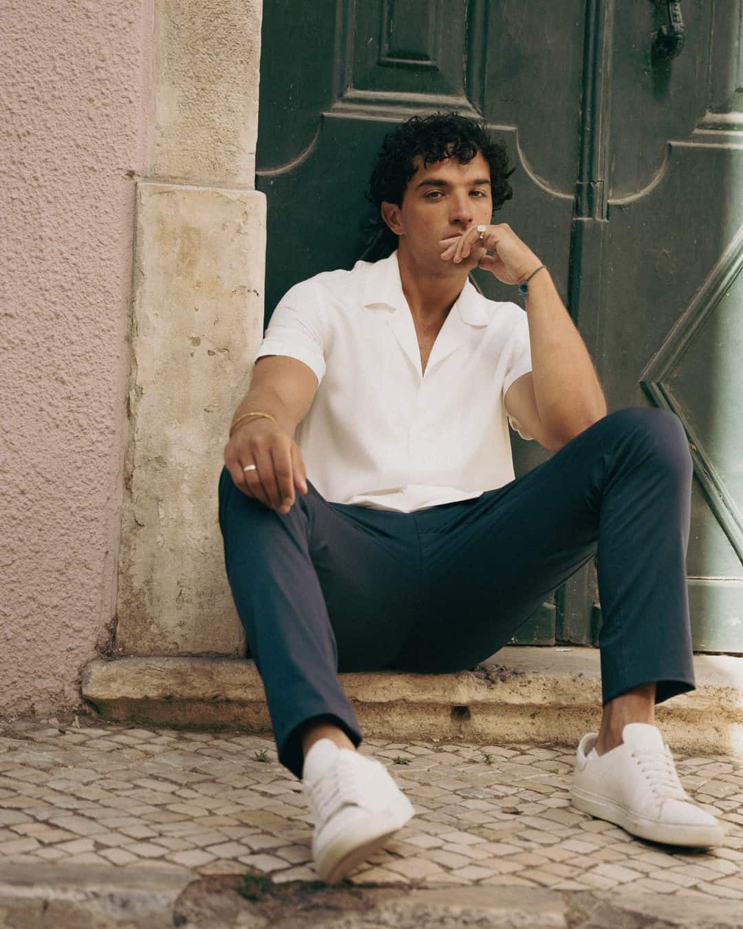 man in casual outfit sitting infront of a doorway