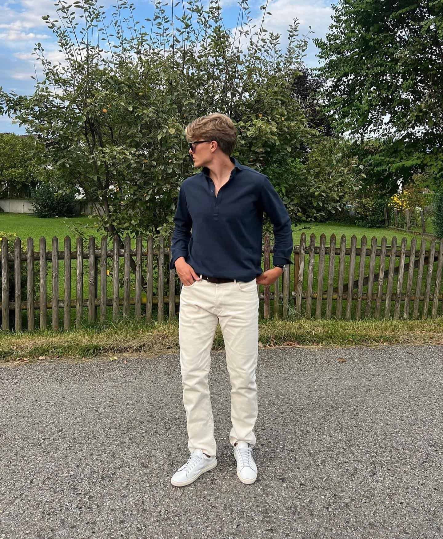 man wearing a navy pique popover shirt and white jeans