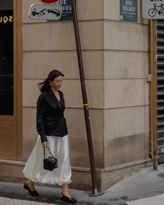 Influencer wears a cream satin skirt.