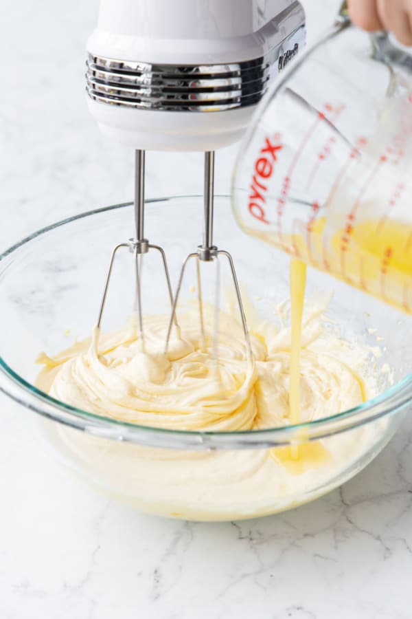 Pouring melted butter into mixing bowl with egg yolk mixture.