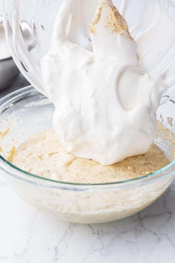 Adding remaining whipped egg whites to mixing bowl with the rest of the cake batter.