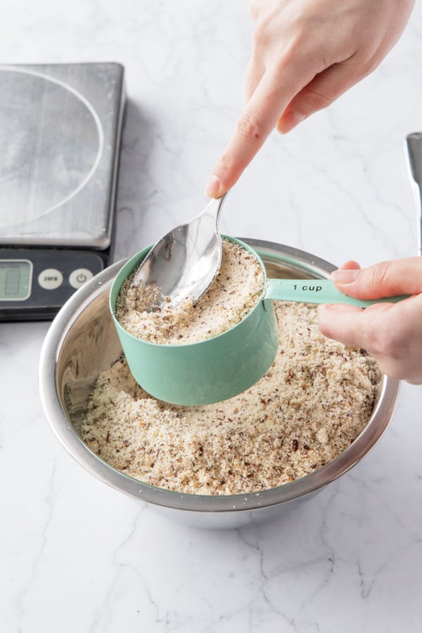 Measuring hazelnut flour by lightly packing it into the measuring cups.