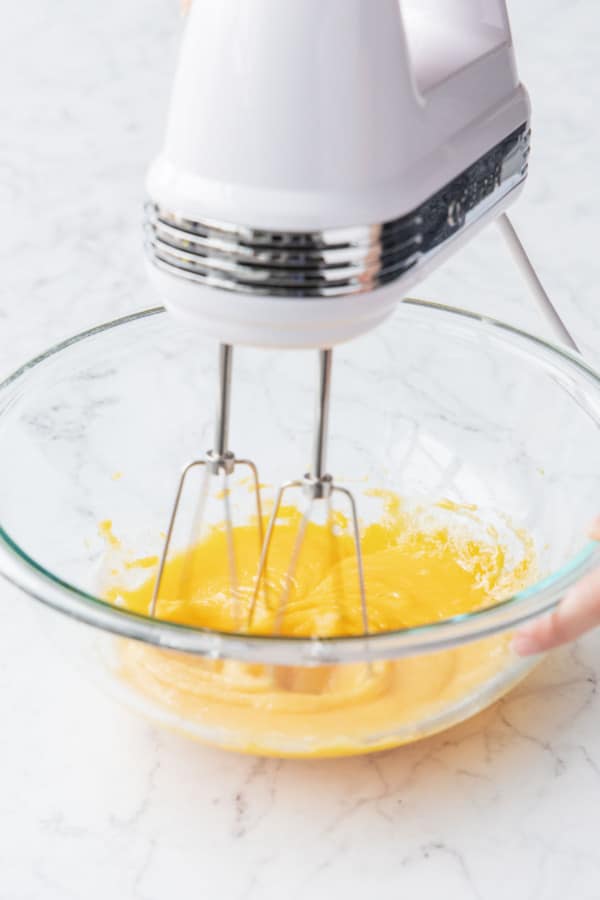 Beating egg yolks with some of granulated sugar using an electric mixer.