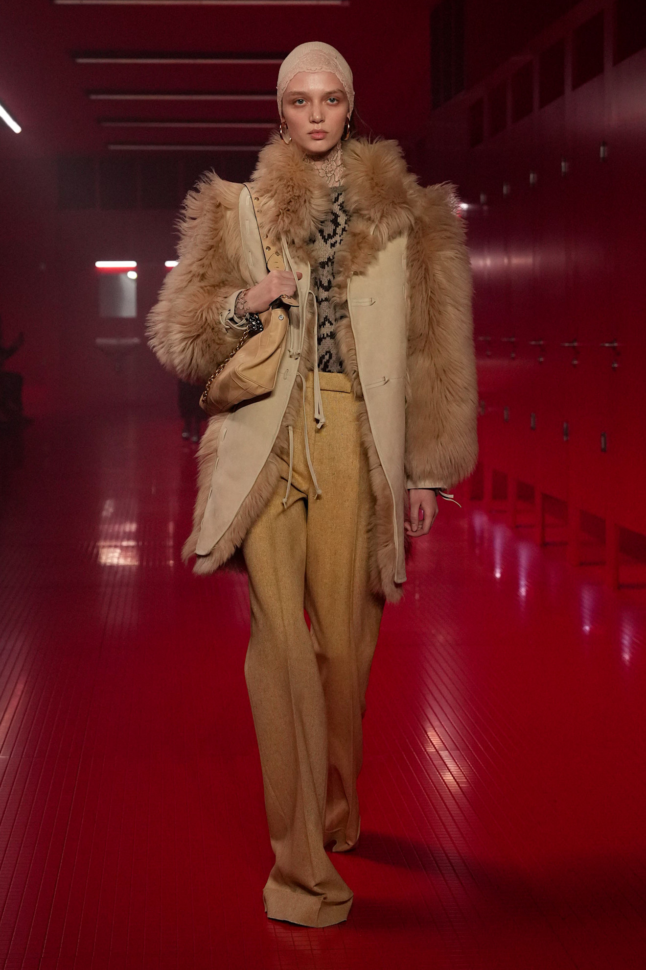 A model walking in the F/W 25 Valentino show during Paris Fashion Week wearing a tan fur coat with a patterned blouse and mustard trousers.