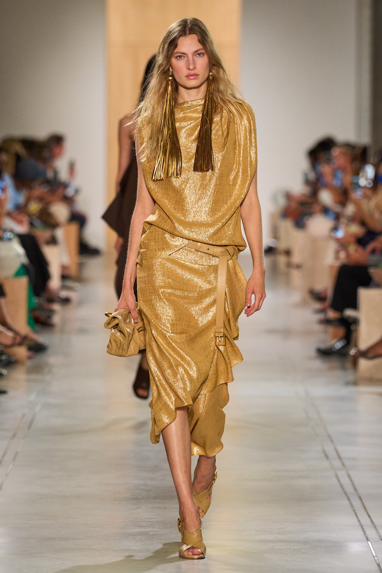 A Michael Kors model wearing a gold metallic dress