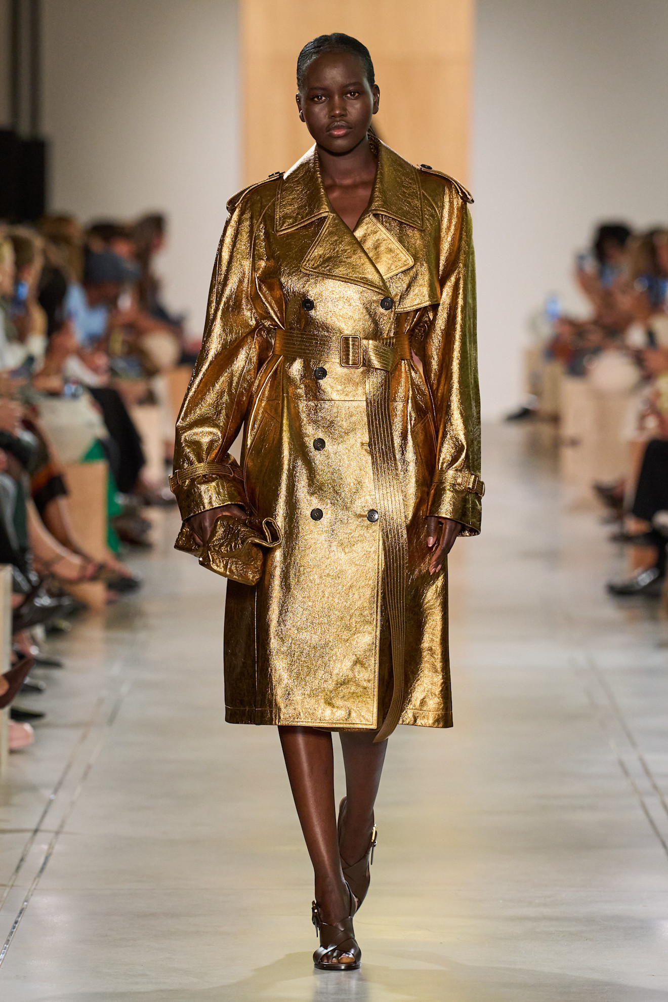 A Michael Kors model wearing a gold metallic trench coat