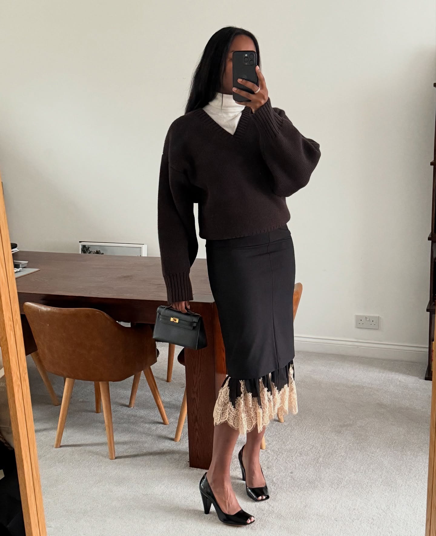 @nlmarilyn wearing a skirt outfit idea for 2026, including a turtleneck under a sweater with a black skirt layered on top of a lace-trim skirt.